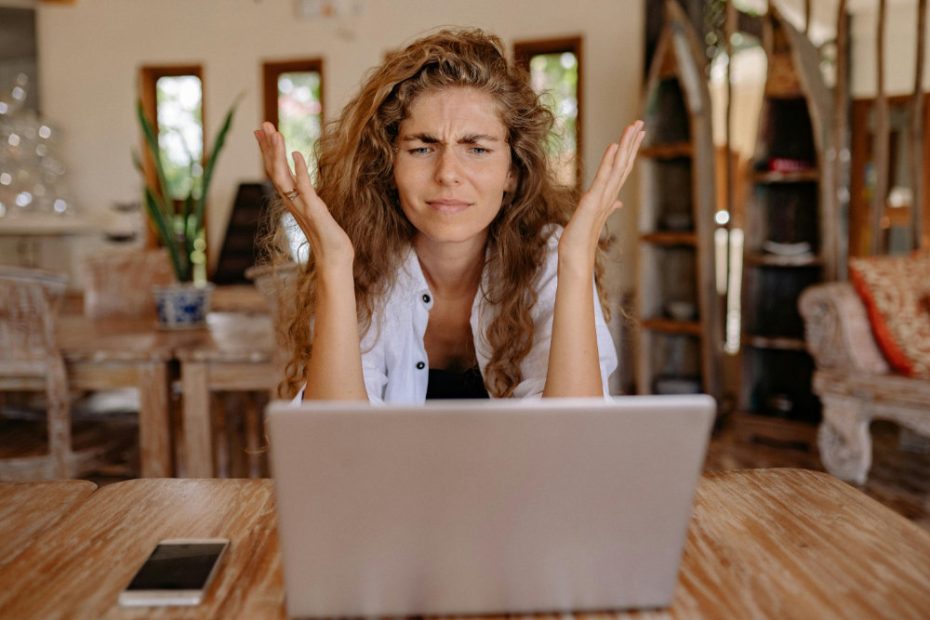 Woman sat at laptop throwing her hands up in frustration